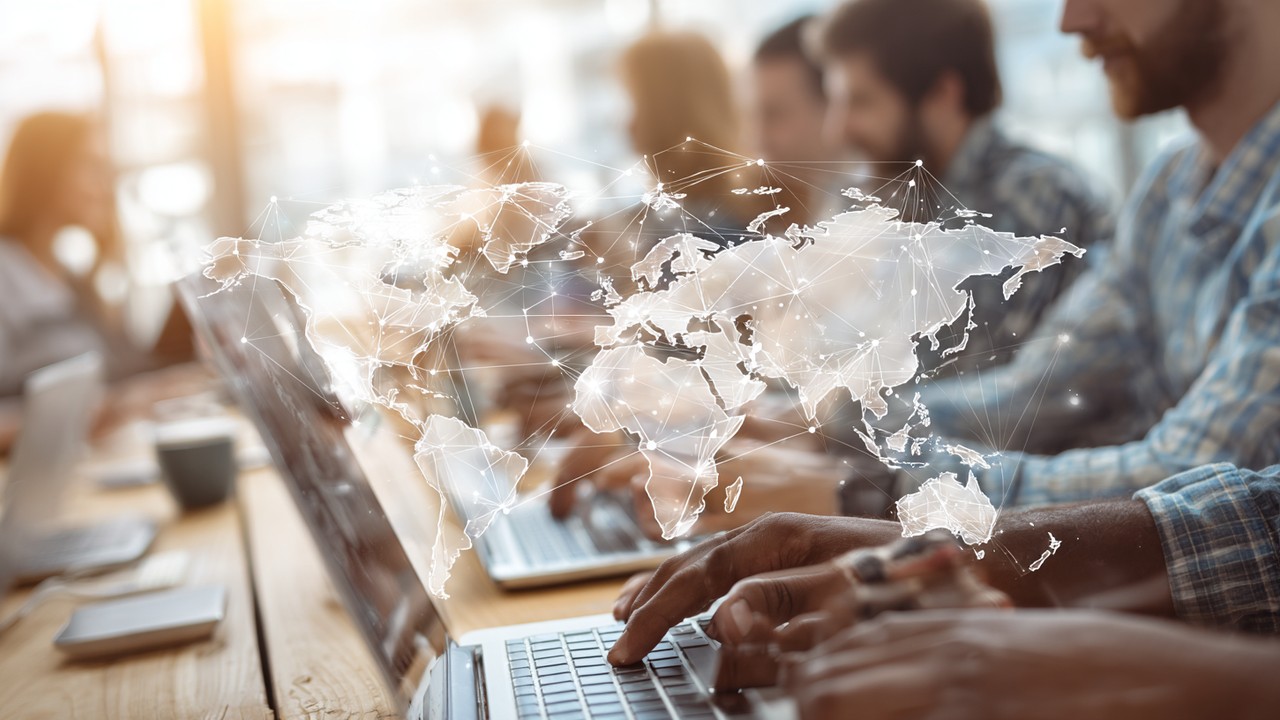 Diverse group of people using laptops and smartphones in a bright modern workspace with world map overlays, symbolizing global connectivity and fast website loading.