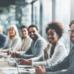 Diverse group of professionals collaborating around a modern conference table in a bright office, showcasing multicultural teamwork.