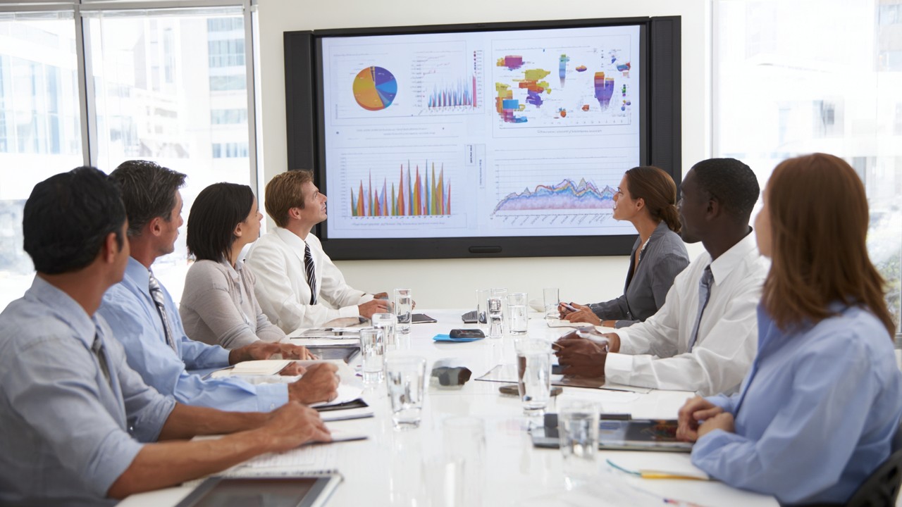 Diverse marketing team analyzing SEO performance charts and localization strategies in a bright conference room, showcasing teamwork.