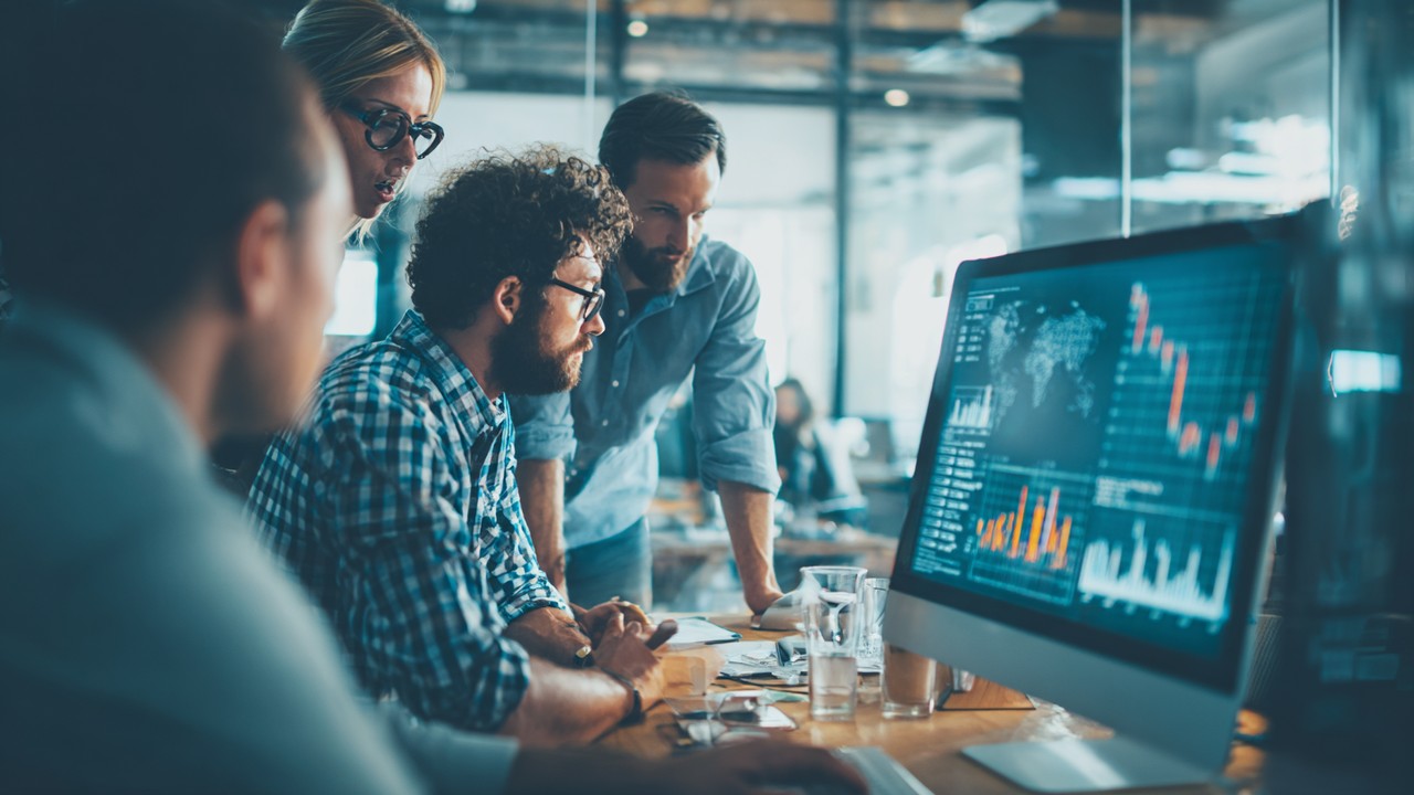 Team collaborating around a large screen displaying website analytics and performance metrics in a modern office, emphasizing teamwork and speed optimization.